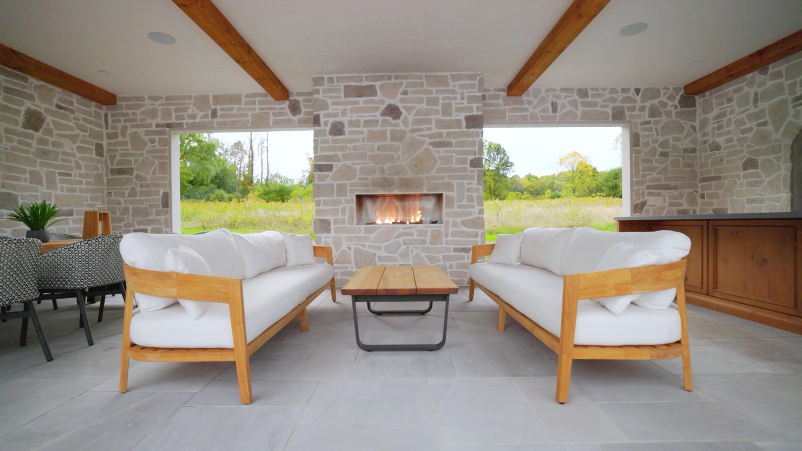 Outdoor luxury living space with white stone fireplace and sofas captured for real estate promo video production.