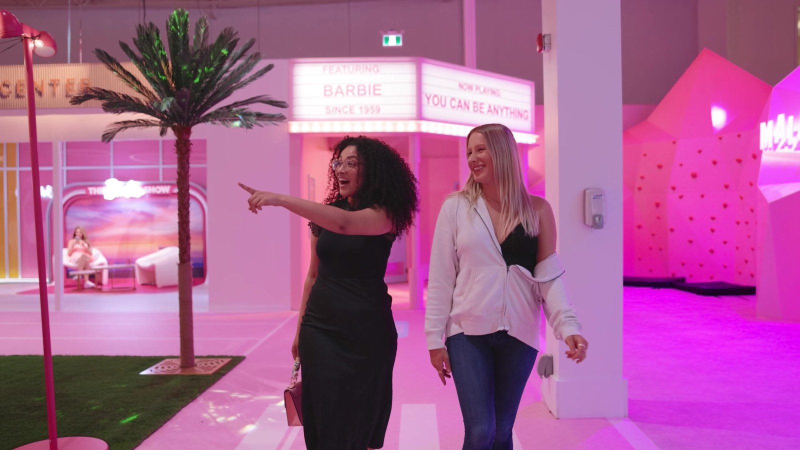 Two women exploring a pink Barbie-inspired town, captured for a promotional video brand spot.